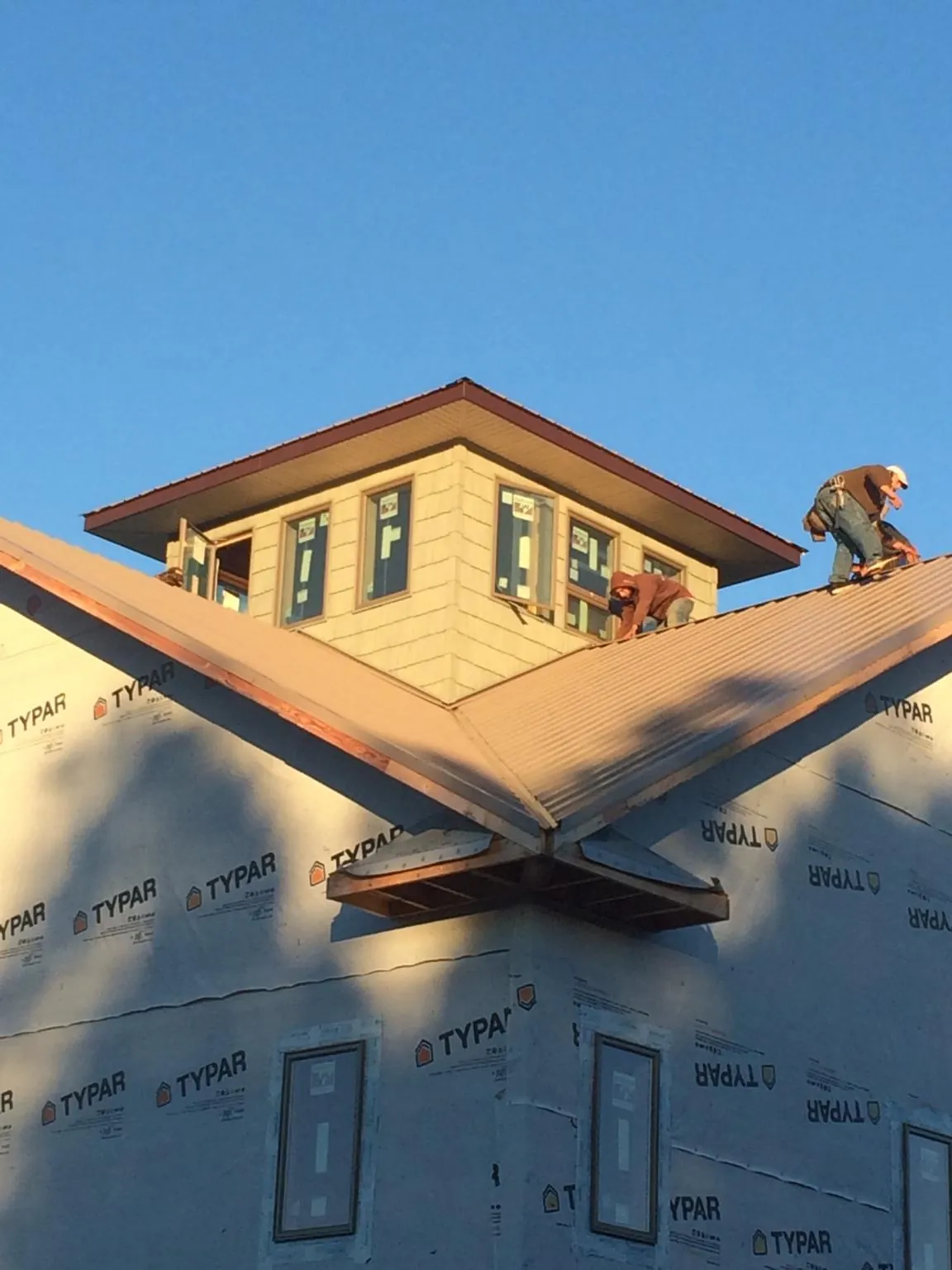 Roofers working around a rooftop cupola on a new metal roof at sunset — Roof Waterproofing in Alden by Roofing Brothers